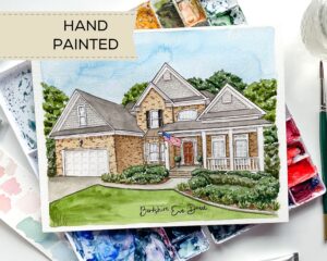 Hand painted watercolor house portrait by Colle Creative sitting on a paint palette.