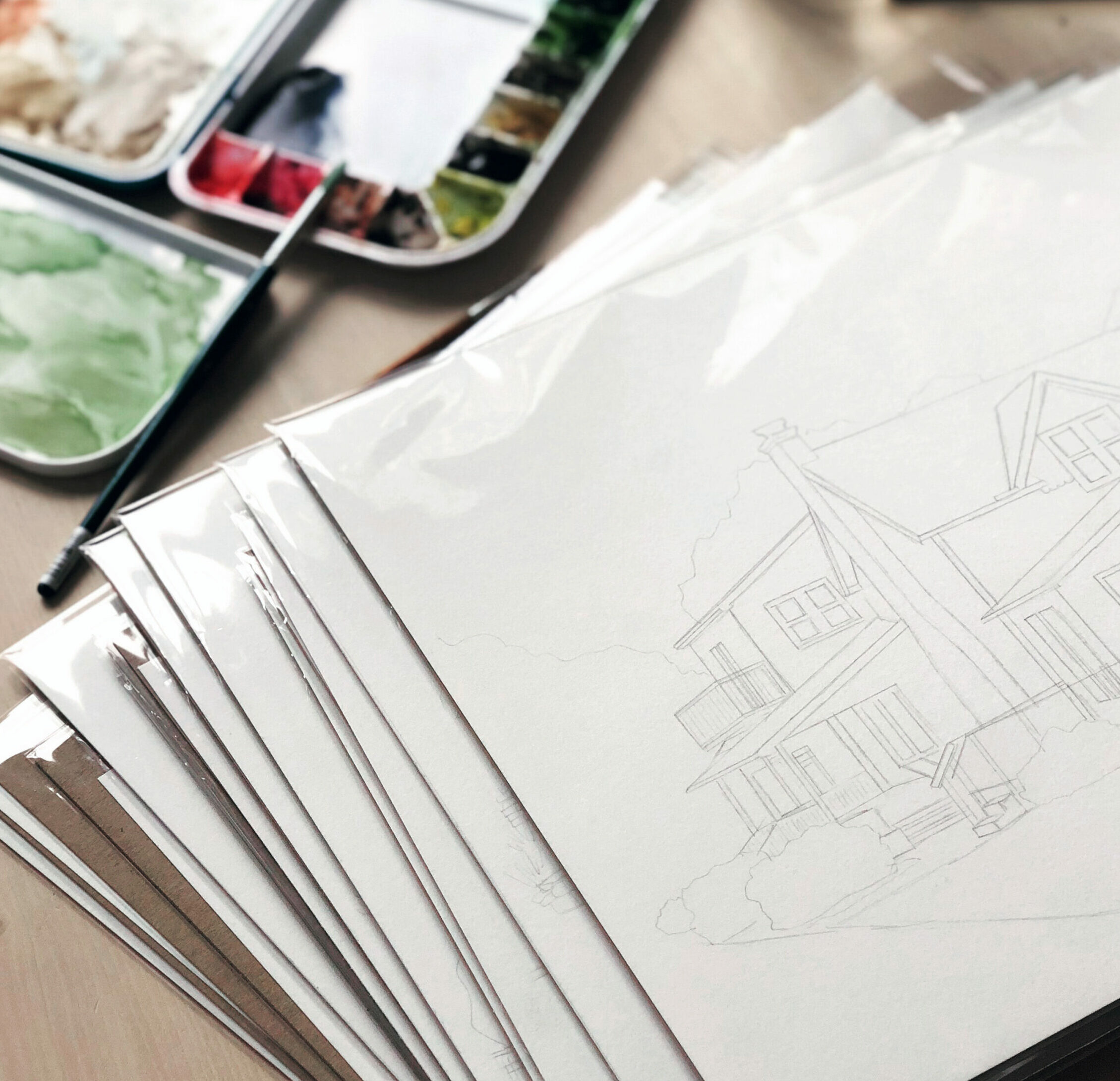 A stack of custom portrait drawings on a table.